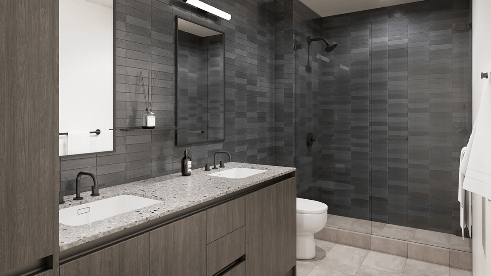 Elegant modern bathroom at Vesper ATX featuring dark grey tiles, a spacious glass-enclosed shower area, a large mirror over a double sink vanity with matte black fixtures, and a terrazzo countertop, providing a contemporary look.